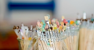 Eine Sammlung von Pinsel in verschiedenen Farben in Gläsern.